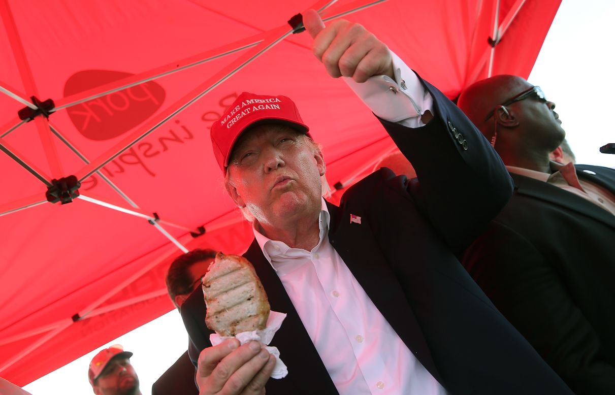 Trump eats a pork chop on a stick and gives a thumbs-up sign to fairgoers while campaigning at the Iowa State Fair on August 15.