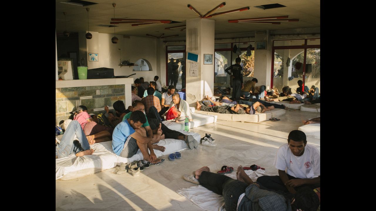 Migrants gather in a makeshift camp at an abandoned hotel.