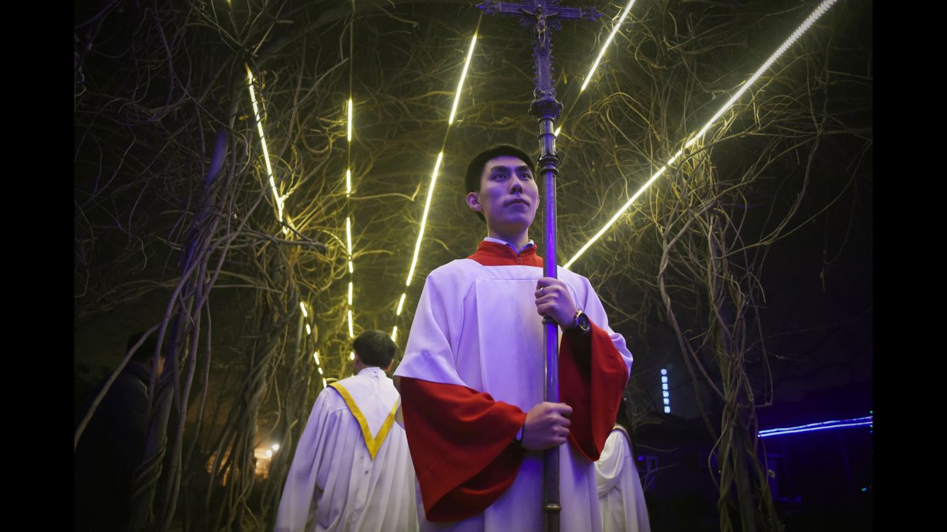 A cross-bearer attends a Christmas Eve Mass at a Catholic church in Beijing on Thursday.