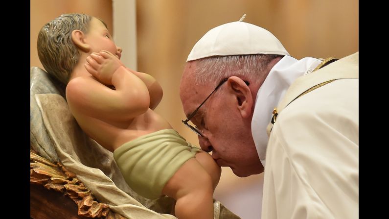 Pope Francis kisses a figurine of baby Jesus during a Mass at St. Peter's Basilica in the Vatican on Christmas Eve.