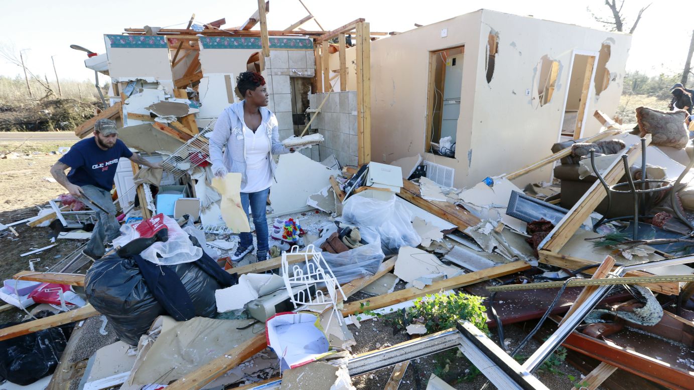 Trista Boga, center, helps salvage what she can from a friend's home along Highway 178 in Holly Springs, Mississippi, on Thursday. At least 14 people were killed in Mississippi, Tennessee and Arkansas as spring-like storms mixed with unseasonably warm weather and spawned rare Christmastime tornadoes in the South.