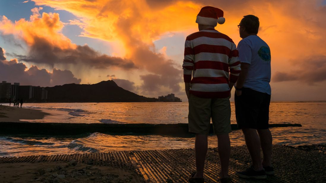 Tourists watch the Christmas Day sunrise behind Diamond Head from Waikiki Beach in Honolulu.