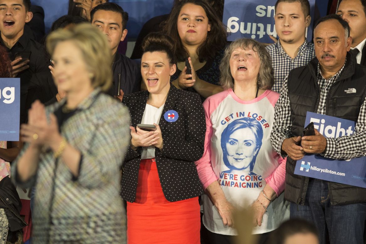A woman behind Hillary Clinton wears a "Get in Loser, We're Going Campaigning" shirt during an event in Dallas on November 17.