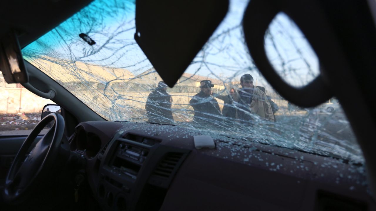 Afghan security personnel are seen through the shattered windshield of a damaged car after a suicide car bomb attack near the Kabul airport in Kabul, Afghanistan.