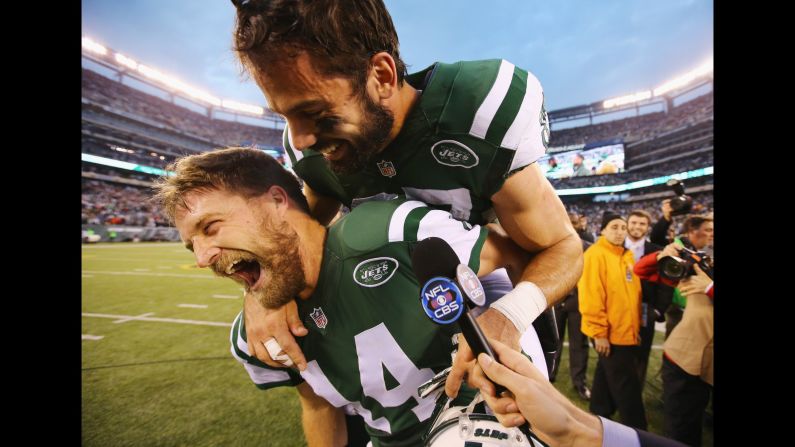 New York Jets wide receiver Eric Decker jumps on the back of quarterback Ryan Fitzpatrick during a television interview Sunday, December 27, in East Rutherford, New Jersey. The two teamed up for the game-winning touchdown as the Jets defeated the New England Patriots 26-20 in overtime.