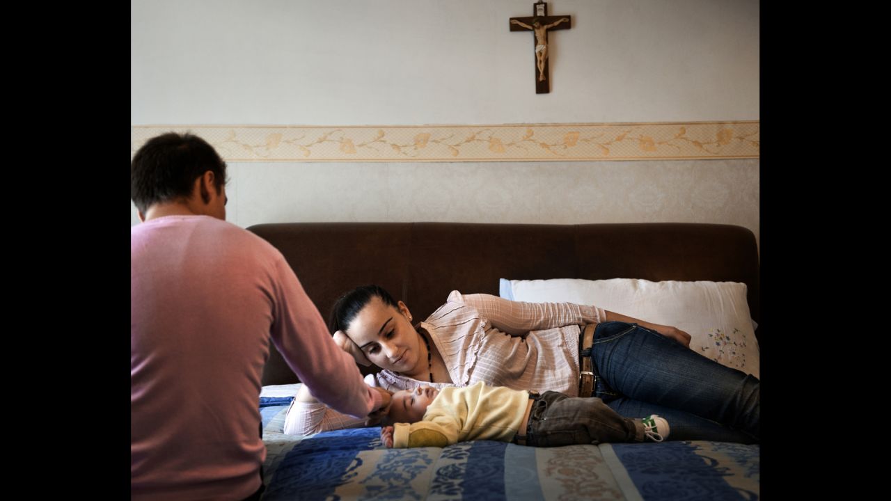Marsia, 15, and her brother Nino are on the bed with Marsia's son, Vincenzo.