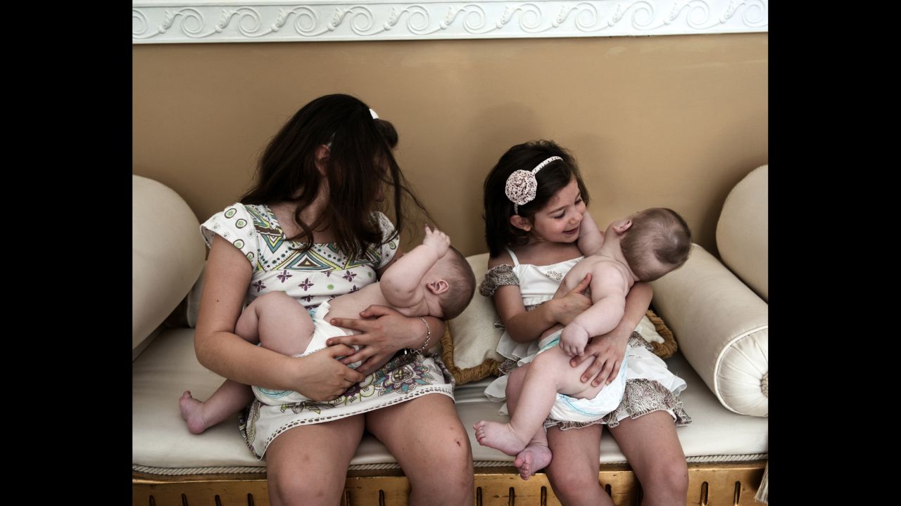 Two young girls look after their older sister's twins. Carmela, 19, has three babies.