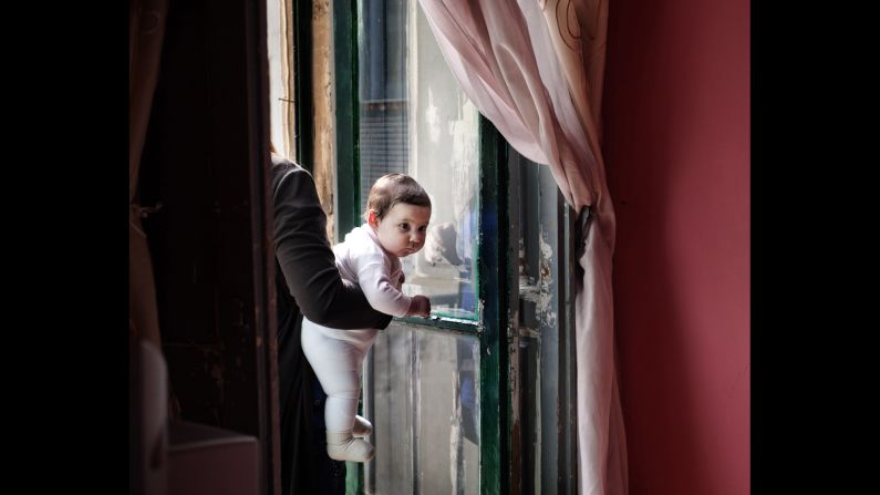 Carla holds Carmen while talking to a neighbor. Many of these young mothers hardly leave their homes, Gengotti said.