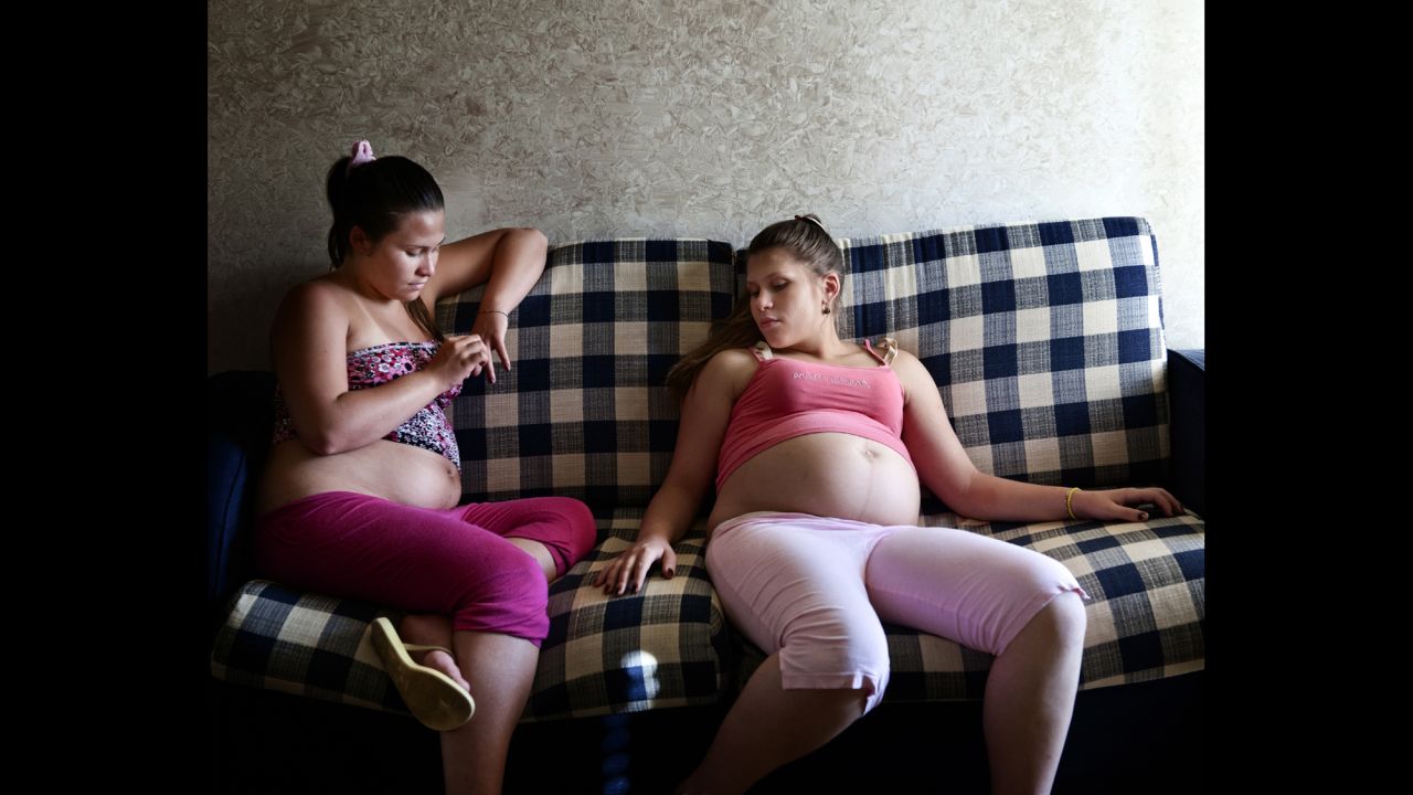 Angela and Virna sit on the couch during their pregnancies.