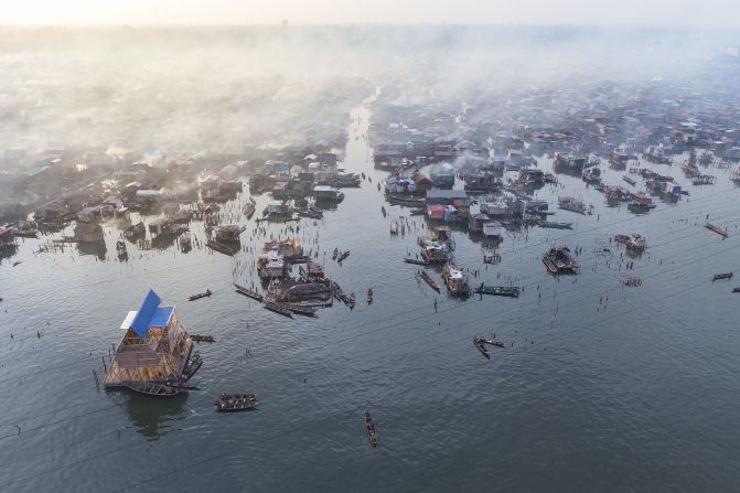An aerial photograph of the Makoko Floating School by Kunlé Adeyemi of NLÉ Architects. Makoko is a large informal community in the center of Lagos where about 150.000 people live in self-built structures on the water. The three-story school is a floating structure at the edge of the community, shot by Iwan Baan in 2013.