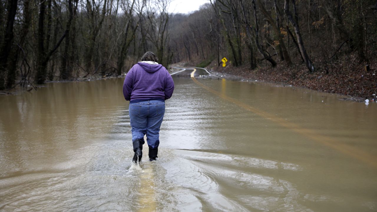A woman walks down a flooded road to get back to her home in Eureka, Missouri, before evacuating on December 28.