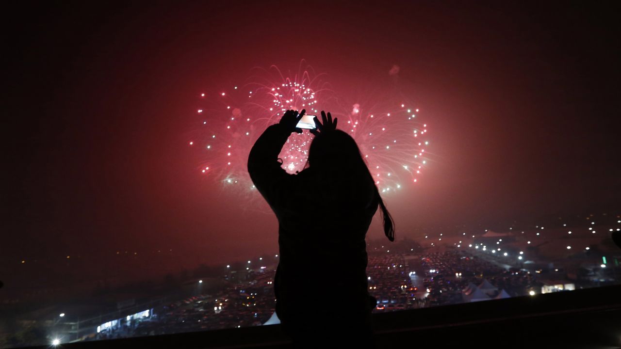 A woman takes a picture of fireworks while celebrating the new year in Paju, South Korea.