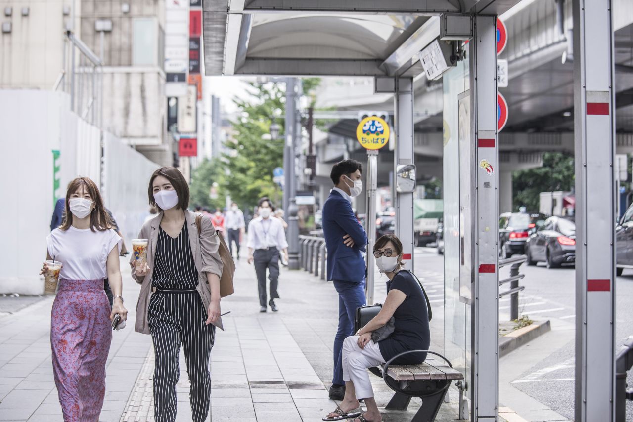 Pedestrians wearing protective masks walk along a sidewalk in Tokyo, Japan, on Thursday, July 30.