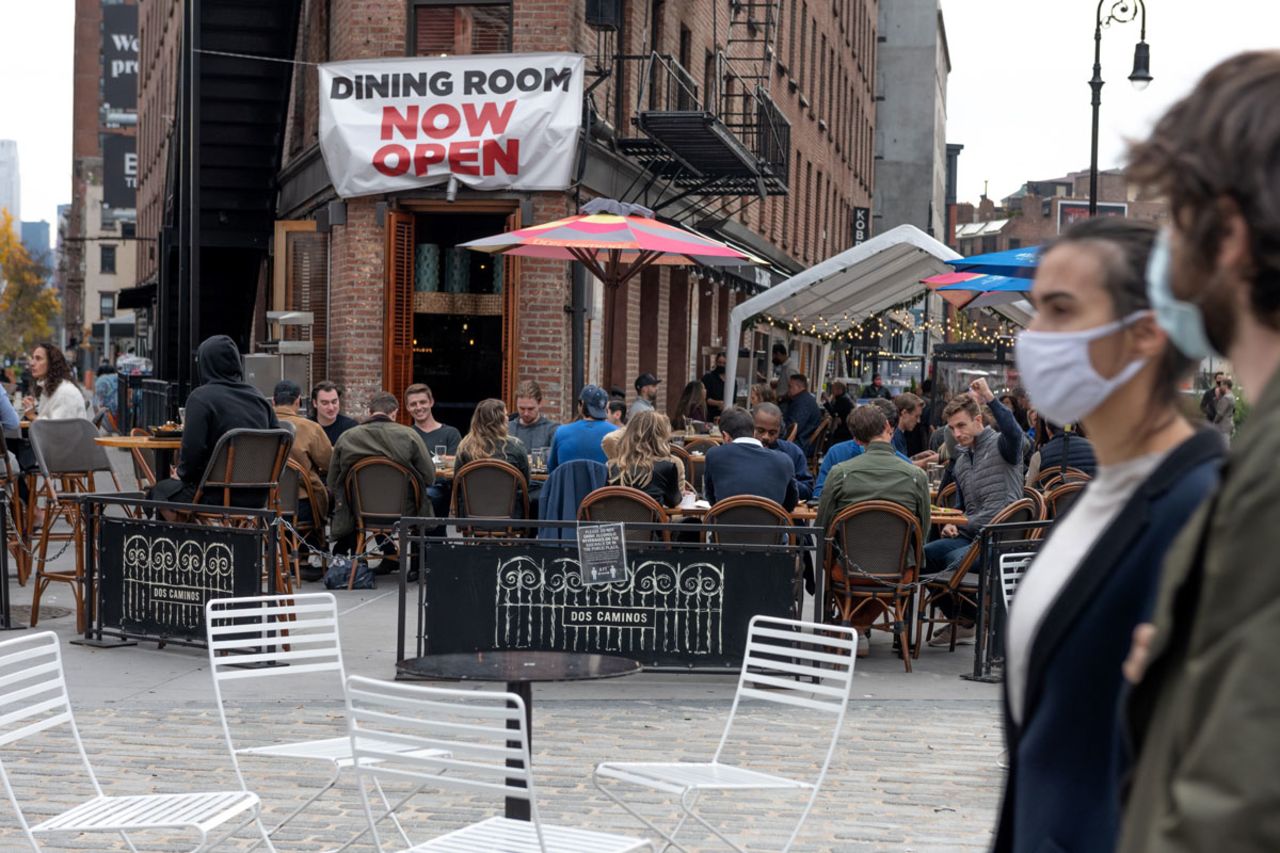 People wearing masks walk by people dining at a restaurant in the Meatpacking district on November 21 in New York City.