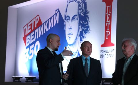 Russian President Vladimir Putin tours the Peter the Great: Birth of the Empire multimedia exhibition in the Russia – My History historic park at VDNKh on June 9. Ivan Yesin, chair of the Russia – My History Association of Historic Parks, left, and Alexander Myasnikov, chief editor of the project, explain the exhibits.