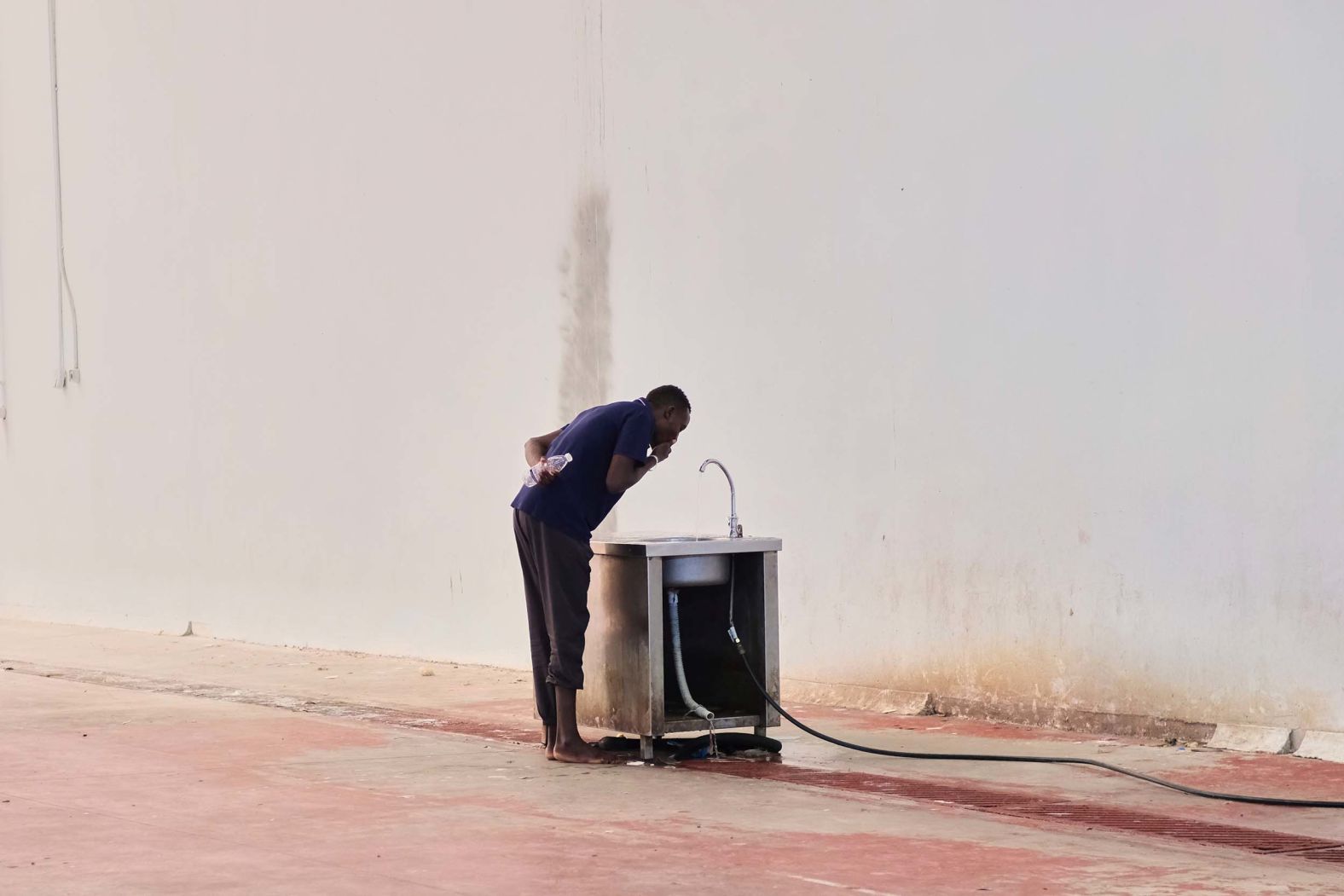 A migrant who recently arrived on the Greek island of Crete drinks water at a temporary shelter on Tuesday, August 19.
