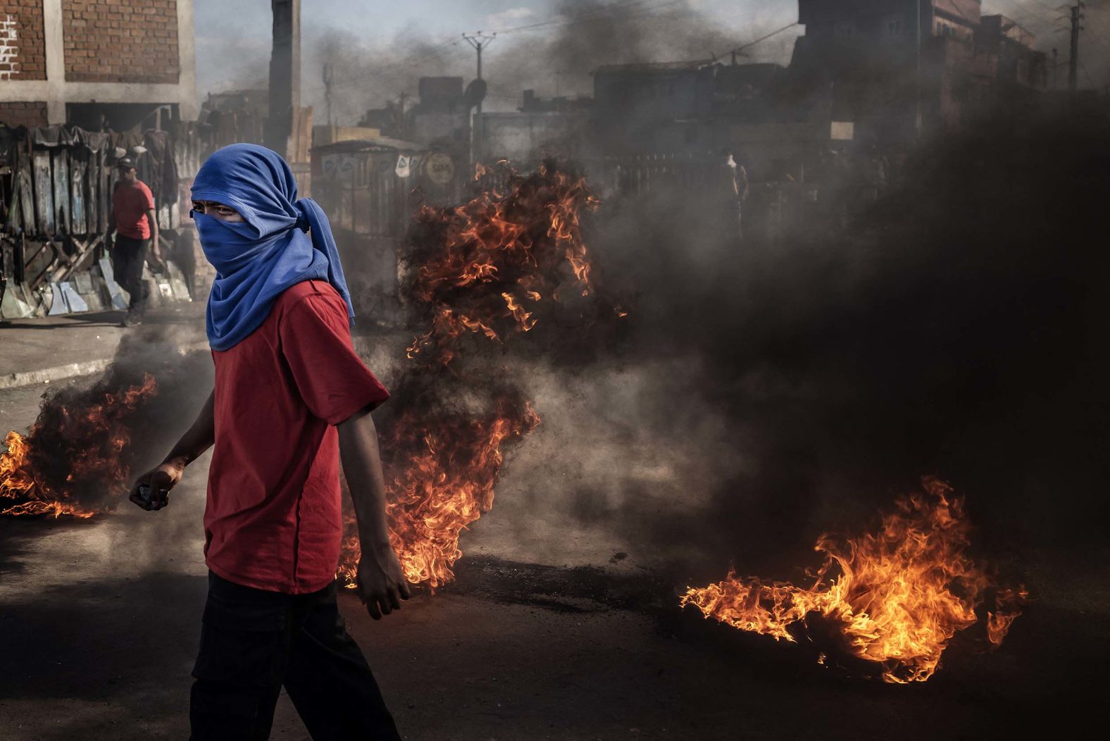 A protester carries stones in front of burning barricades during a demonstration in Antananarivo, Madagascar, on Tuesday, October 7. Madagascar President Andry Rajoelina said last month that he was dissolving the government following <a href="index.php?page=&url=https%3A%2F%2Fwww.cnn.com%2F2025%2F09%2F29%2Fafrica%2Fmadagascar-gen-z-protests-intl">youth-led protests over water and power cuts</a>. At least 22 people have been killed in clashes, and more than 100 have been injured, according to the Reuters news agency.