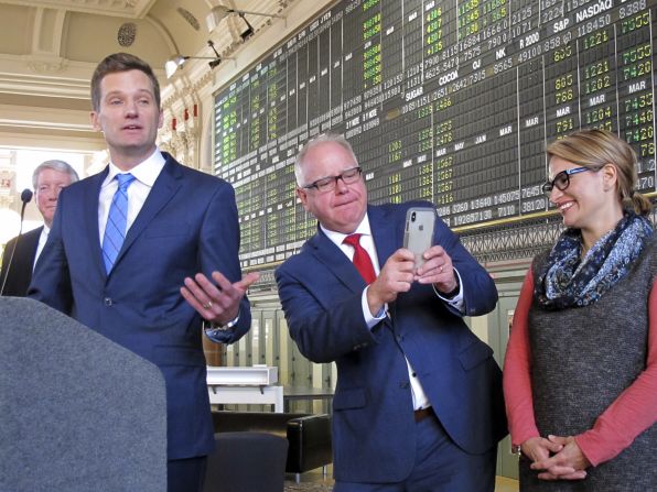 Walz, as governor-elect, leans to get a picture of the wife and children of Steve Grove, left, in January 2019. Grove was Walz's new commissioner of employment and economic development. At right is Peggy Flanagan, the incoming lieutenant governor.