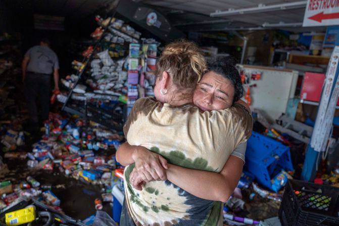 Cassandra Randall, right, is hugged by Jessica Downey inside a damaged Maddie's grocery store in Steinhatchee, Florida, on Friday.