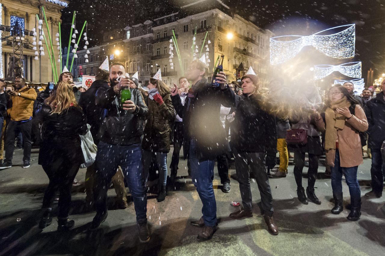 People pop bottles of champagne as they celebrate the new year in the historic center in Brussels.