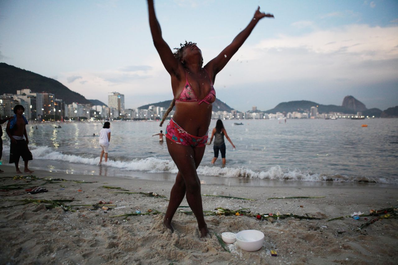 A reveler tosses rice in the air on Copacabana beach in Rio de Janeiro, Brazil.  