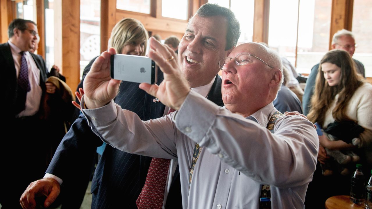 New Jersey Gov. Chris Christie, a Republican presidential candidate, poses for a photo with a visitor after speaking at a coffee house in Muscatine, Iowa, on Tuesday, December 29.