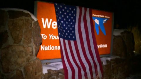 Protesters drape an American flag over the wildlife refuge's sign.