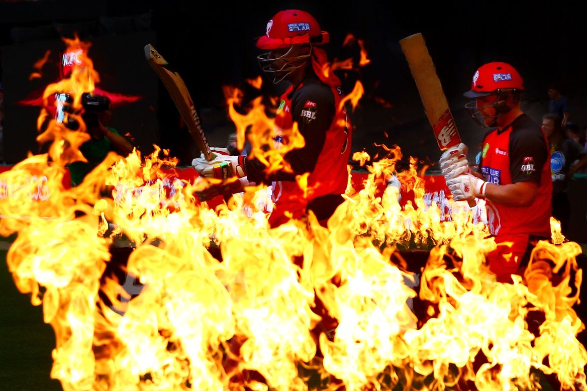 Cricketers Chris Gayle, center, and Aaron Finch walk through flames before a Big Bash League match in Melbourne on Wednesday, December 30. Gayle and Finch play for the Melbourne Scorchers.