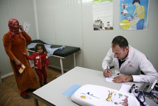 Refugees coming from previously middle-income countries often face the challenge of paying privately for healthcare, when it was previously free in their home country. Pictured, a Syrian-Kurdish refugee mother and daughter visit a clinic at the Domiz refugee camp.