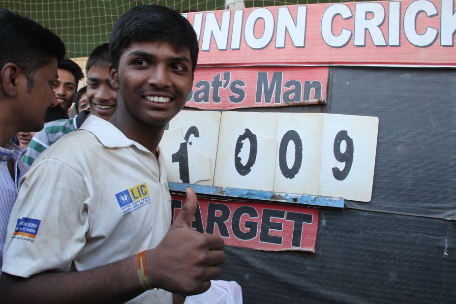 Pranav Dhanawade poses next to the scoreboard showing his historic innings of 1,009 not out.  