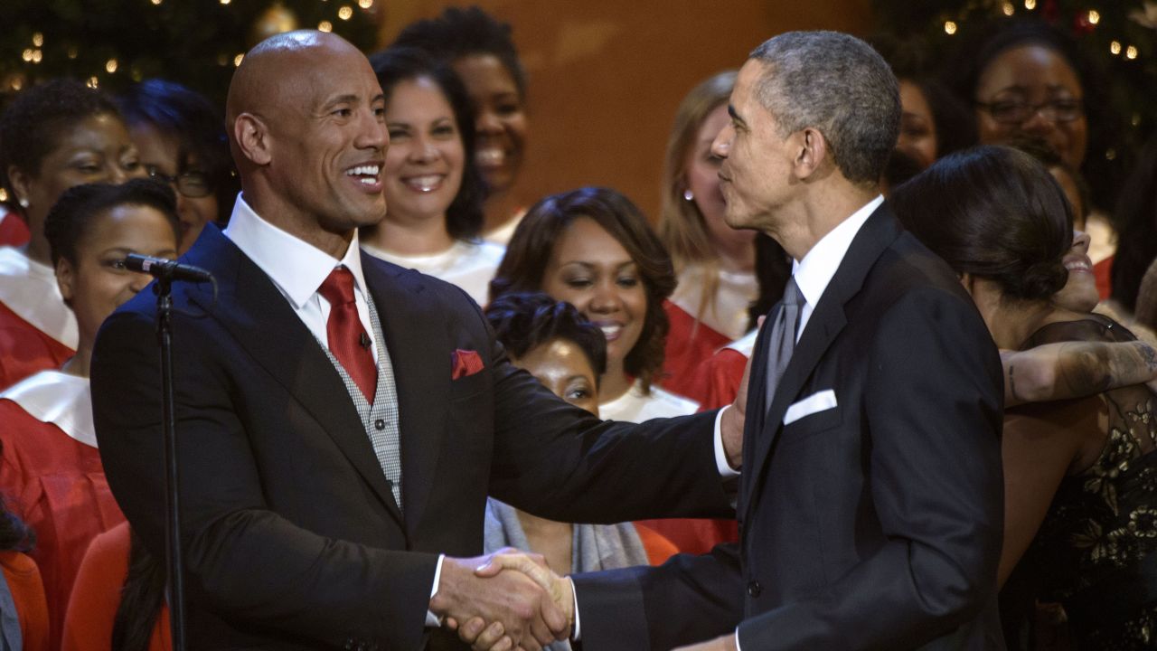 Dwayne "The Rock" Johnson and former US President Barack Obama shake hands during a taping of the Christmas in Washington concert at the National Building Museum December 14, 2014 in Washington, DC.