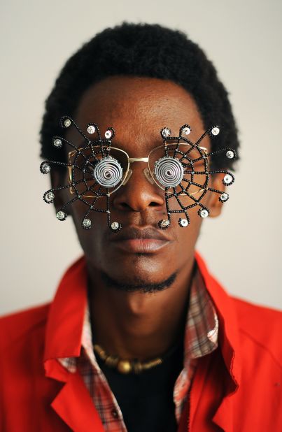 Kabiru created thrifty artworks made from found objects for his "C-Stunners" series. Here, he poses with one of his creations. The series is inspired by his father, who once fell out of love with his own spectacles after receiving a beating from his parents for breaking them.