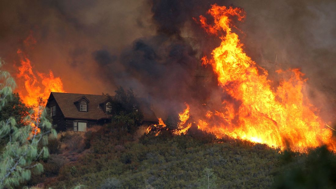 Flames from the Rocky Fire approach a house on July 31 in Lower Lake, California. Wildfires burned more than 10 million acres in the United States during 2015, the most on record and 40% more than in an average year. 