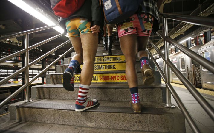 Two men clad in colorful underwear walk up subway steps in New York.  