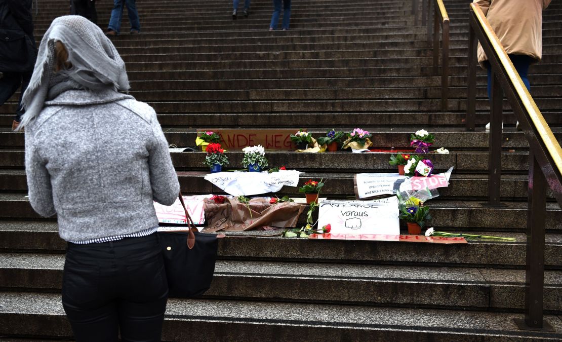 A woman looks at flowers and messages laid on steps in front of Cologne's main train station.