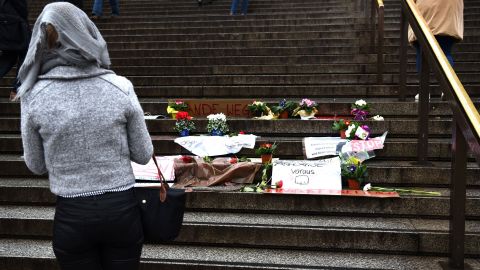 A woman looks at flowers and messages laid on steps in front of Cologne's main train station.