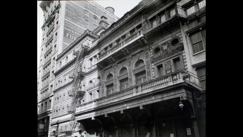 Twelve blocks south, the ornate Fifth Avenue Theater sits on Broadway in 1938. On the building next door, advertisements promote fur and clothing.