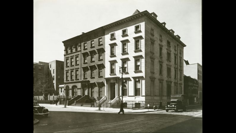 Three row houses, including one made of marble on the right, sit in the sun in 1936. Trolley tracks run past them on Eighth Street.