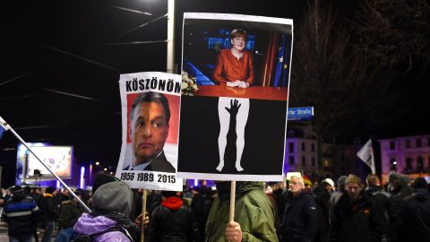 Protesters in Leipzig hold aloft posters depicting German Chancellor Angela Merkel being groped and of Hungarian PM Viktor Orban, known for his anti-migrant stance. The latter reads "Thanks" in Hungarian.