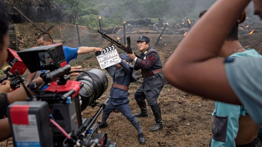 HENGDIAN, CHINA - AUGUST 11:  (CHINA OUT) A film worker signals the take  as Chinese actors playing Nationalist soldiers prepare for a scene during  filming of a battle segment in the series "Legend of the Stupid Guy" set during the second Sino-Japanese War on August 11, 2015 in Hengdian, China. Seventy years after the end of World War II, there is still widespread resentment across China toward Japan and its wartime misdeeds. It is estimated that hundreds of films depicting China's victory over Japan in 1945 are produced on the mainland every year and the genre remains one of the country's most popular entertainment draws. The conflict and what critics say is a refusal by most Japanese leaders to fully apologize for history, has long set the tone for strained relations between the two countries and and at times fuelled regional tension. Many of the films are shot in and around Hengdian Studios, Asia's largest production facility.  (Photo by Kevin Frayer/Getty Images)