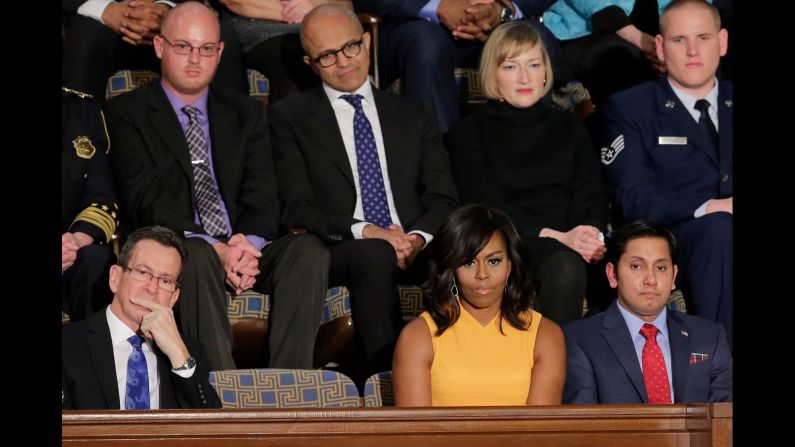 First lady Michelle Obama sits beside an empty chair as her husband speaks. The chair represents the victims of gun violence in America.