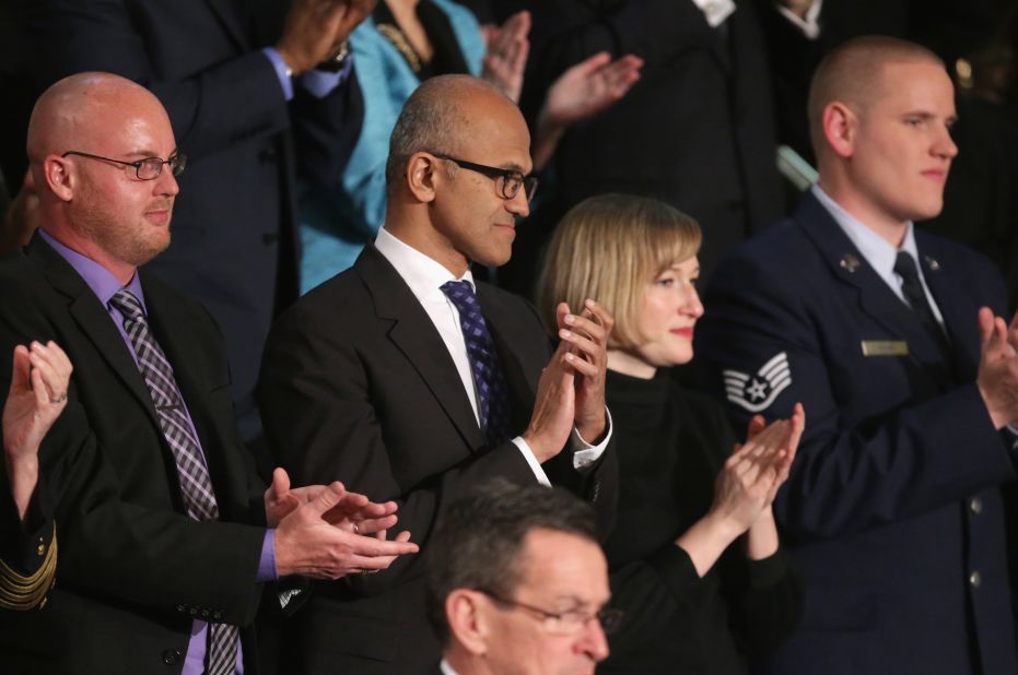 Satya Nadella, CEO of Microsoft, center, claps as people enter the chamber.