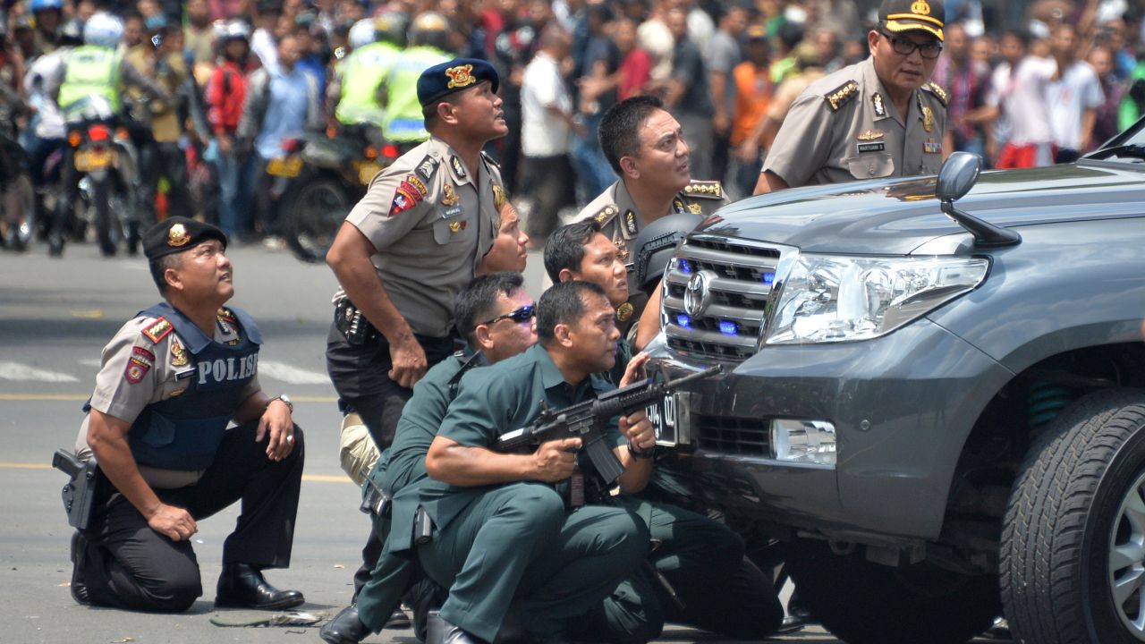 TOPSHOT - Indonesian police take position behind a vehicle as they pursue suspects after a series of blasts hit the Indonesia capital Jakarta on January 14, 2016. A series of bombs killed at least three people in the Indonesian capital Jakarta on January 14, with shots fired outside a cafe as police moved in, an AFP journalist at the scene said.     AFP PHOTO / Bay ISMOYO / AFP / BAY ISMOYO        (Photo credit should read BAY ISMOYO/AFP/Getty Images)