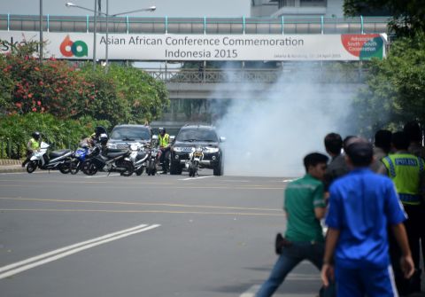 Police hide behind vehicles during an exchange of gunfire with suspects hiding near a Starbucks cafe when another blast took place in Jakarta on January 14.