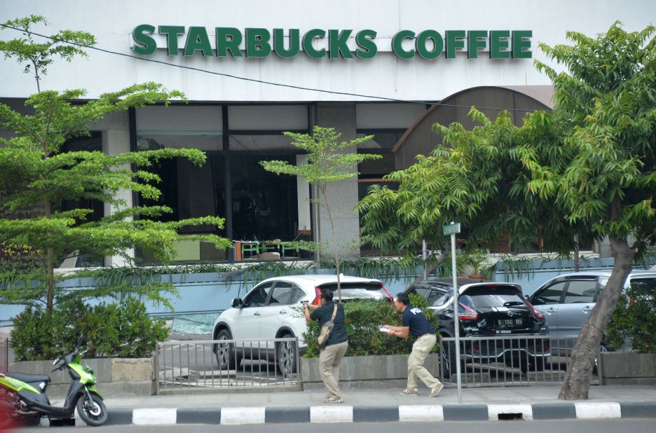 Plainclothes police officers aim their guns at suspects outside a cafe after a series of blasts hit the center of Jakarta on January 14.
