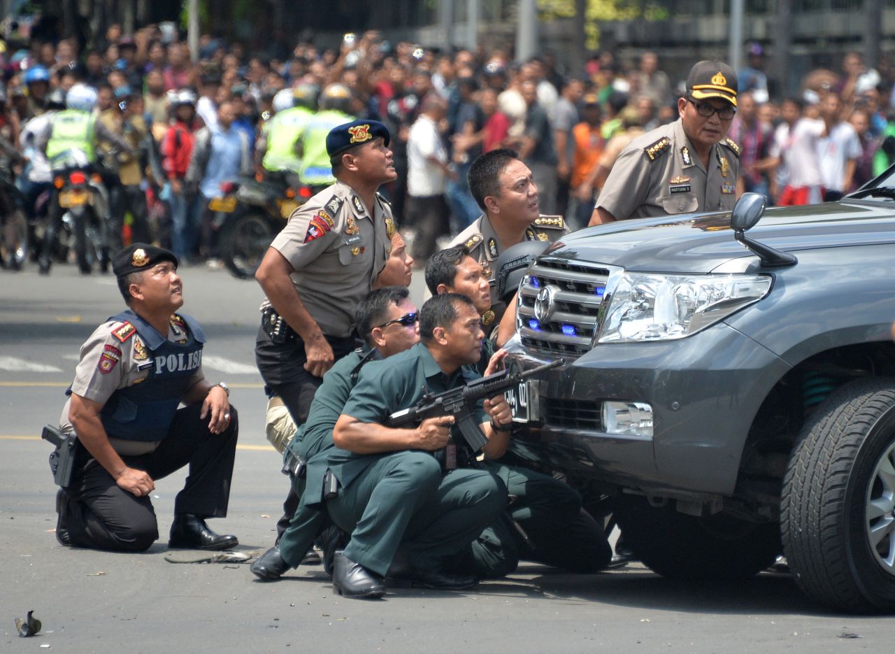Indonesian police take position behind a vehicle as they pursue suspects after a series of blasts hit the center of Jakarta on January 14.