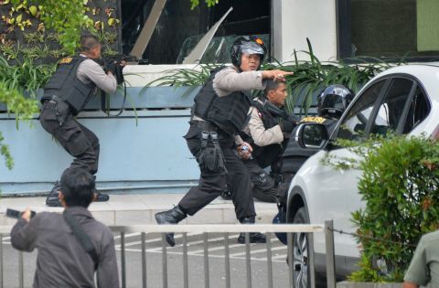 Indonesian police take position and aim their weapons as they pursue suspects outside a cafe after explosions went off in Jakarta on January 14.