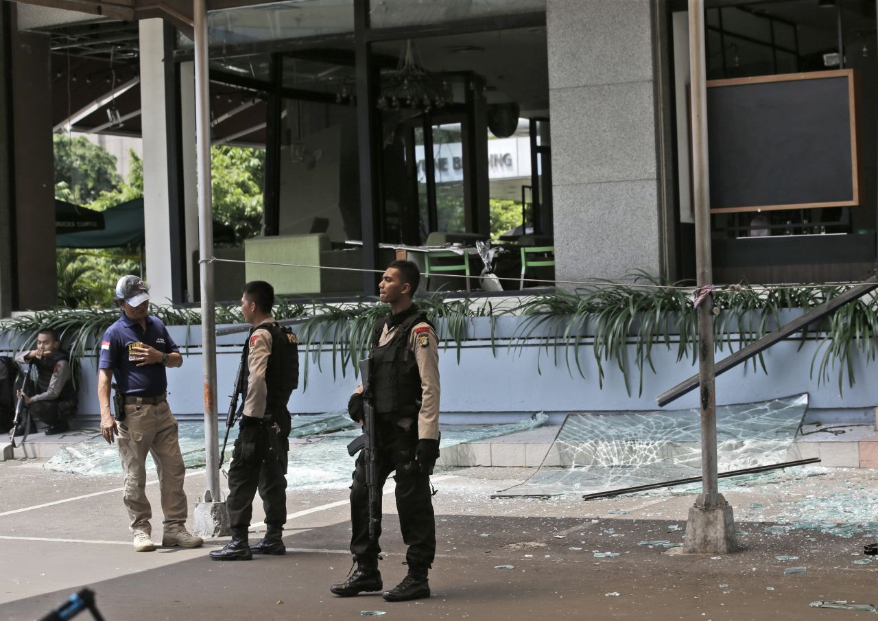 Armed police officers keep watch outside a damaged Starbucks cafe after an attack in Jakarta on January 14.