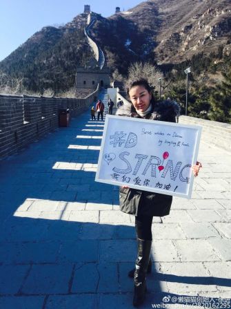Beijing resident Xu Jin poses with a sign saying "#DStrong" on the Great Wall, on the city's outskirts.