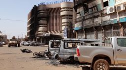 Burnt out cars with the Splendid Hotel, left rear, which suspected militants attacked in Ouagadougou, Burkina Faso, Saturday, Jan. 16, 2016. The overnight seizure of a luxury hotel in Burkina Faso's capital by al-Qaida-linked extremists ended Saturday when Burkina Faso and French security forces killed four jihadist attackers and freed more than 126 people, the West African nation's president said. (AP Photo/Baba Ahmed